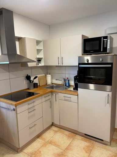 Moderne Küche mit Holzarbeitsplatte, Herd, Mikrowelle und Backofen.